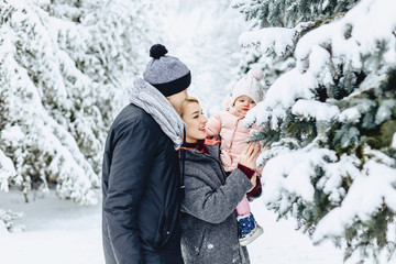 Fototapeta na wymiar happy young family walks with baby on winter street, mom, dad, child