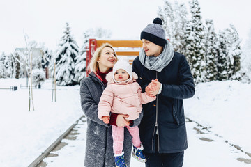 happy young family walks with baby on winter street, mom, dad, child