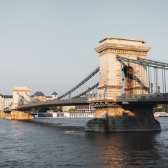 Obraz premium Szechenyi Chain Bridge in beautiful Budapest at sunset. Bridge over the Danube River, connects the two banks of the Buda and Pest, in the capital of Hungary.