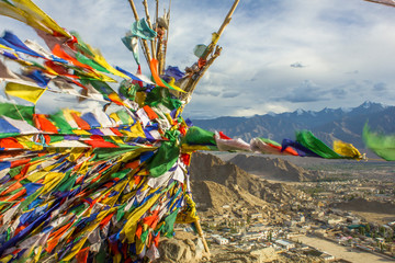 Tibetan prayer flags on a mountain overlooking the mountains and the village in the valley