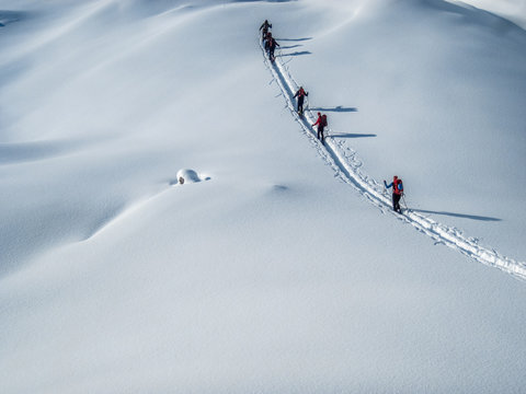 Ski touring in deep powder snow. Alpinists with ski on a ski tour on a glacier. Background image of a winter alpine landscape and ski alpinists off piste. Winter adventure activities.
