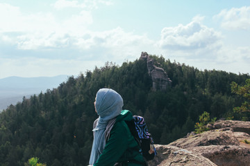 Muslim girl on mountain looks at the lake and forest