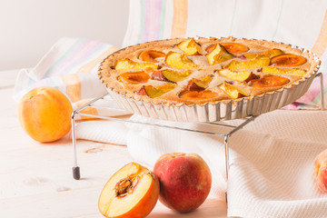 Open pie with peaches in almond cream on a white wooden background. Delicious and sweet peach tart