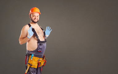 Funny fat bearded repairman on a gray background.