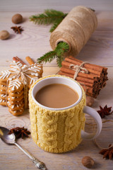 Obraz na płótnie Canvas Knitted yellow cup with hot winter drink, cookies, cinnamon, decorations. Cozy