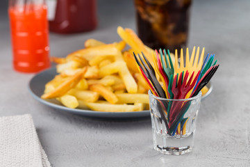 French fries potatoes fried on a plate with decorative colored forks