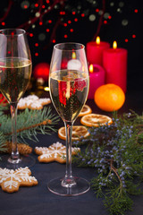 Champagne glasses in holiday setting. Christmas and New Year celebration with champagne. Christmas holiday decorated table with white sparkling wine, candles and watch