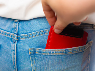 Close-up of a the hand of thief stealing the wallet to a woman.