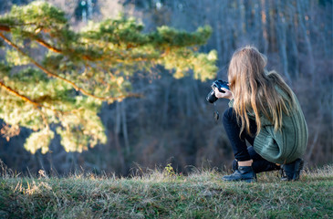 A young female photographer takes pictures of a beautiful landscape. Travel and photography.