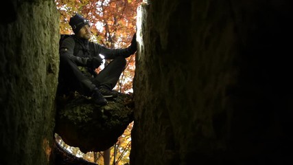 Caucasian Caver in His 30s with Flashlight Relaxing on the Rock Formation.