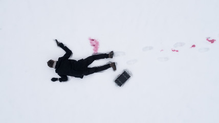 Dead man on snow with gun and case of cash. View from above.