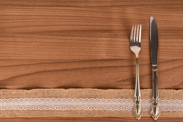 Silver fork and kitchen knife on wooden table. Eat concept flat lay, top view.