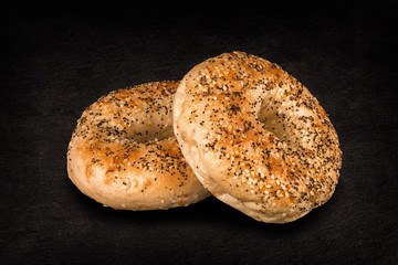 Fresh poppy seed bagel bread, isolated on a natural slate stone in background.