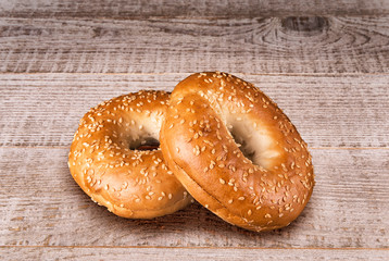 Fresh sesame seed bagel bread, isolated on a white wooden table in background.