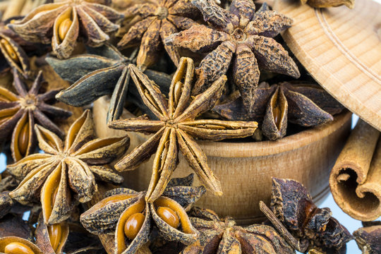 A bowl from a tree is complete asterisks of anise and stick of cinnamon by close up.