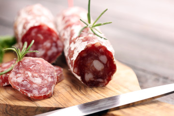 thinly sliced salami on a wooden texture on the background.