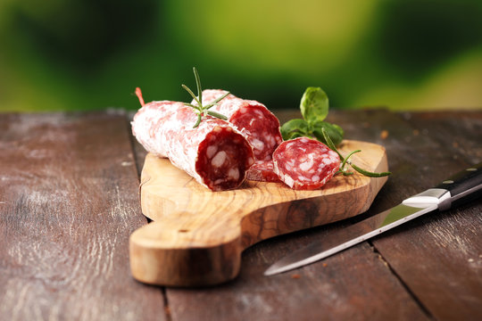 thinly sliced salami on a wooden texture on the background.