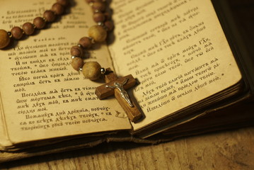 an old prayer book and wooden rosary in the dark