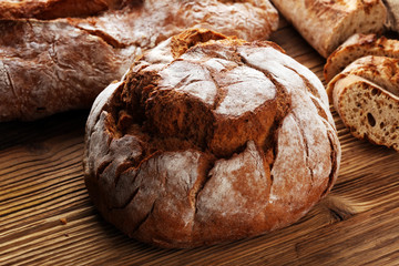 Different kinds of bread and bread rolls on board from above. Kitchen or bakery