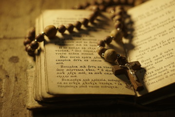 an old prayer book and wooden rosary in the dark