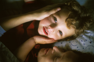 A mother is tucking her kid to bed.