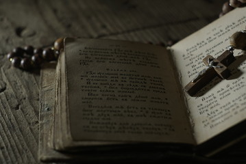 an old prayer book and wooden rosary in the dark