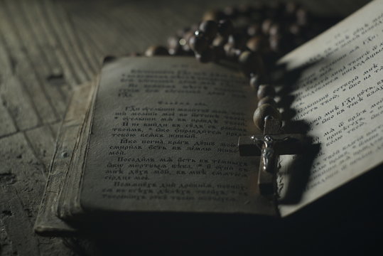 an old prayer book and wooden rosary in the dark