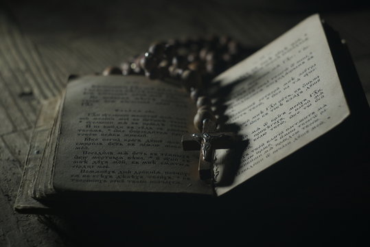 an old prayer book and wooden rosary in the dark