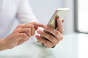 Close-up of male hands using smartphone. Unrecognizable businessman sitting at table and using mobile app. Gadget concept