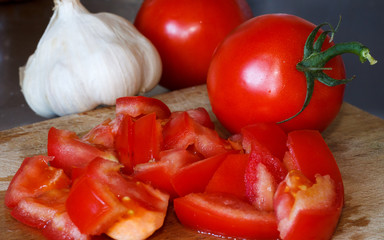 Chopped tomato on wooden board with garlic on side