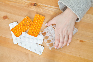 A lot of medicines on night table in bedroom. Woman taking pills.