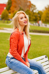 Obraz premium Portrait of happy smiling beautiful young blonde woman in blue jeans and red jacket