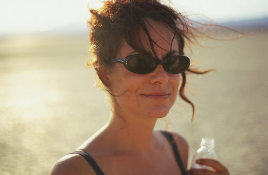 Young woman wearing sunglasses and holding a water bottle while outdoors.