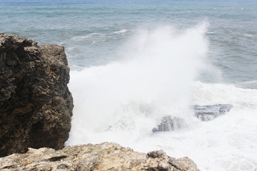 Big splash in the ocean against rock