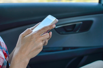 Closeup on person holding using mobile phone on the car interior background, modern smart computer apps solution and online network.