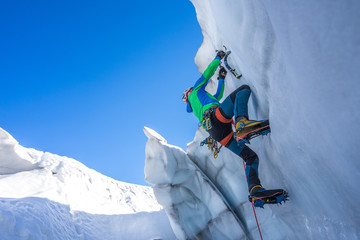 Epic shot of an ice climber climbing on a wall of ice. Mountaineer and climber on an adventure...
