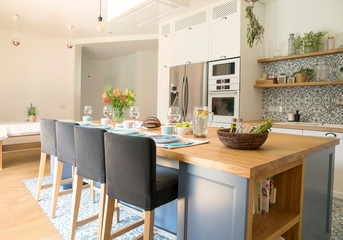 Fresh summer breakfast in Mediterranean style kitchen. Bright and sunny space with a lot of herbs and plants. Modern kitchen with open space.