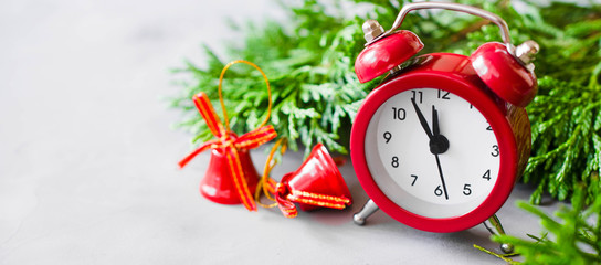 Christmas composition: xmas fir branches, alarm clock and red bells.