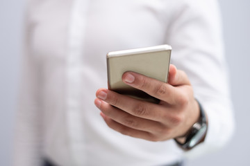 Close-up of male hand holding mobile phone. Caucasian businessman networking on smartphone. Mobile communication concept