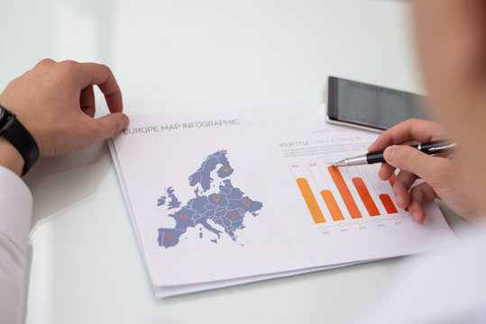 Close-up of male hands working with Europe sales statistic report. Caucasian businessman sitting at table and examining financial paper. Marketing concept