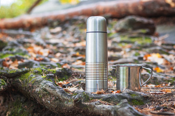 Stainless steel thermos and mug in forest