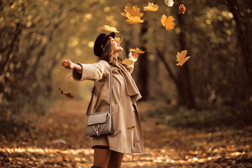 Pretty stylish woman with fashion makeup in autumn park is wearing hat and coat