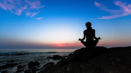 Silhouette of yoga meditation woman on the Sea during amazing sunset.