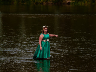 Portrait of a cheerful young woman in a river dressed with a green party dress