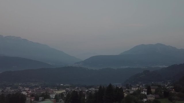 Aerial view of Levico Terme, Italy during sunrise with drone flying forward