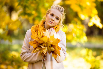 Pretty blonde girl with bouquet of yellow maple leaves