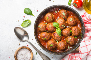 Meatballs in tomato sauce on white table.