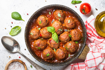 Meatballs in tomato sauce on white table.