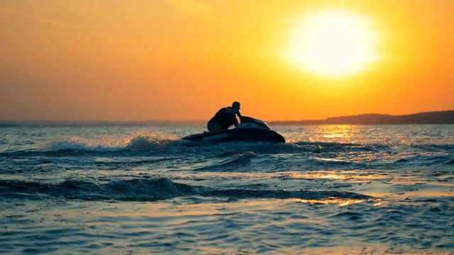 Sunset waterscape with a man jet-skiing.
