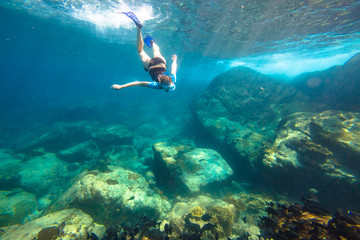 Young woman snorkeling in the blue waters of the popular Similan Islands in Thailand, one of the tourist attraction of the Andaman Sea.